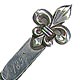 This bookmark was made in the US by Thomas F. Brogan of New York. It is marked with the makers hallmark which is a 5 pointed star and the word sterling. The top is a figural fleur de lis. The date is 1893.