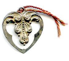 This bookmark was made in the US by an unknown manufacturer. It is a tiny repousse heart shape with a red string tassel and is marked sterling.