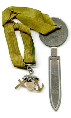 This bookmark was made in Europe around the turn of the 20th century. It is silver plate with a bronze medallion of a cherub. Attached to the top is a yellow-green silk ribbon with three brass and enamel charms attached. The cross, heart and anchor represent faith, hope and charity.