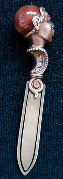 This brass bookmark was made in France by an unknown manufacturer. It depicts the head of an African warrior with diamond eyes and an agate marble head. It has the remnants of a bronze finish.