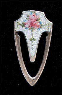 This bookmark is made in the US by F.A. Hermann Co. It is marked with the manufacturers hallmark and is also marked Sterling. The front is enamel with a picture of three roses.