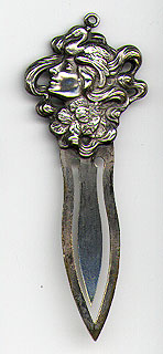 This bookmark was made in the US by an unknown manufacturer. It is silverplate over brass and depicts an art nouveau lady head with a bird and flowers. The date is 1900 - 1910.