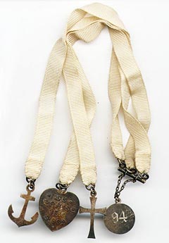 This bookmark was made in the US by an unknown manufacturer. It is marked only sterling. It is a bible bookmark with 4 charms, three at the end of silk ribbons and one on top. The heart charm says "We praise thee oh God." The date is 1894.